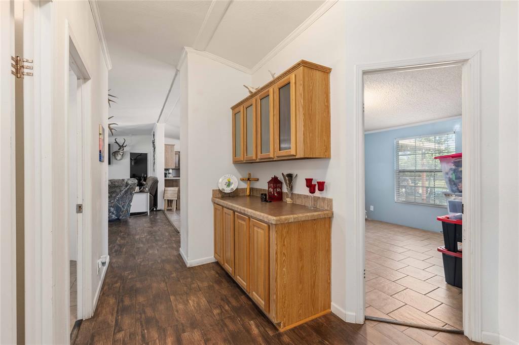 Hallway featuring built-in cabinetry with wood-finish doors, glass-fronted upper cabinets, and a solid-surface countertop