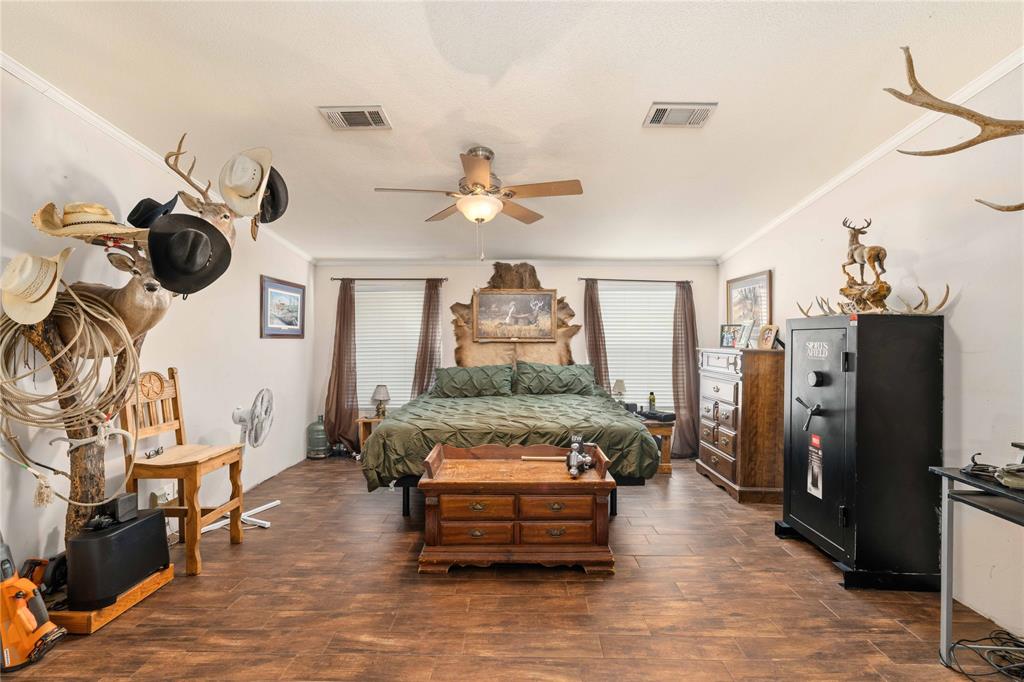 Wood-finish tile flooring, ceiling fan with integrated lighting, and dual windows with crown molding
