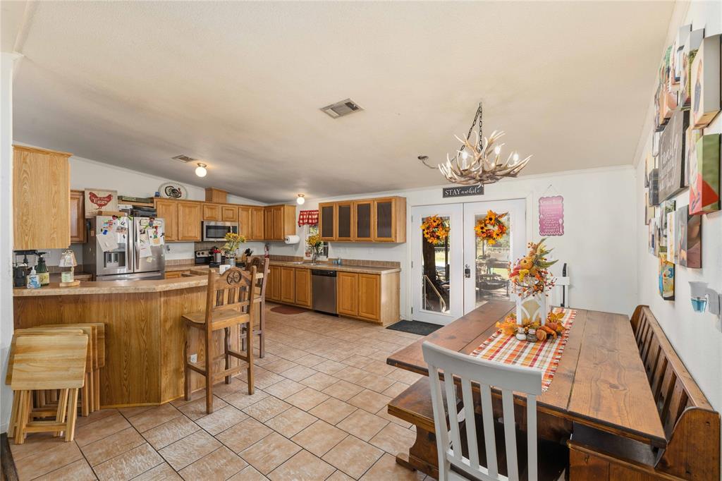 Kitchen featuring wood cabinetry, stainless steel appliances, breakfast bar, tile flooring, and a decorative chandelier