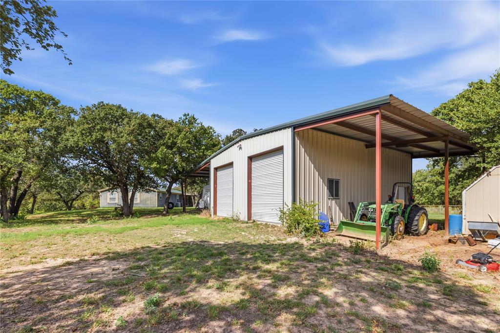 Metal-sided workshop featuring two roll-up doors and a covered carport extension