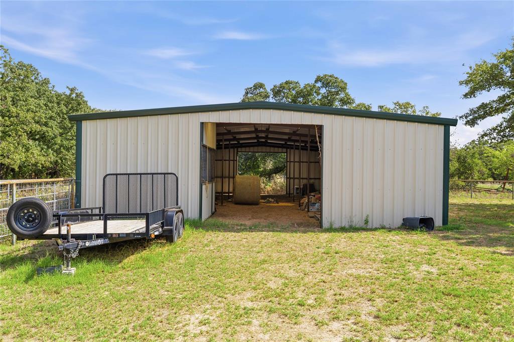 Metal-clad agricultural structure featuring a wide open-entry bay, exposed steel framing, and an earthen interior floor