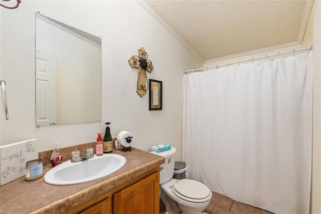 Bathroom featuring an integrated vanity with an oval sink, solid-surface countertop, wood-finish cabinetry, frameless wall-mounted mirror, and tile flooring