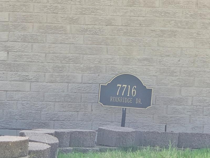 Exterior masonry brick wall featuring a decorative address plaque and stacked stone hardscaping