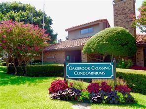 Exterior featuring clay tile roofing, brick facade, stone-textured chimney, and mature landscaping