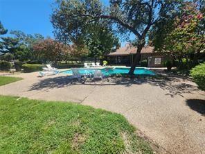 Backyard featuring an in-ground swimming pool, concrete patio, mature trees, and established landscaping