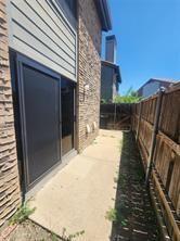 Exterior featuring a stone veneer facade, horizontal siding, sliding glass door, concrete walkway, and wood privacy fencing