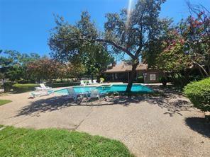 In-ground swimming pool featuring a concrete surround, mature shade trees, and integrated landscaping