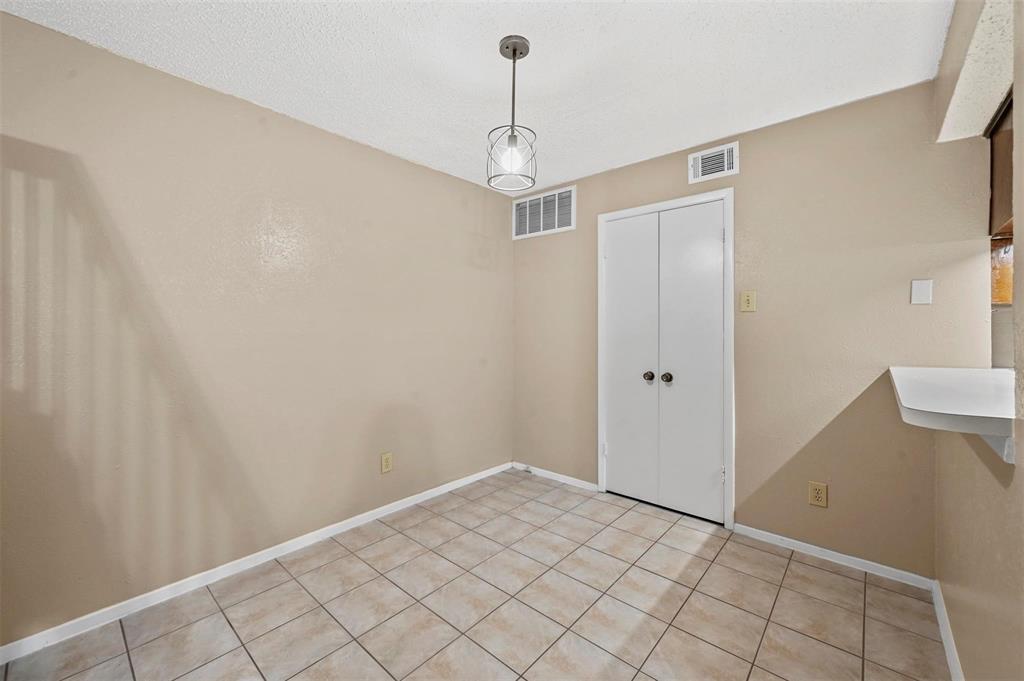 Ceramic tile flooring, neutral wall tones, double-door closet, and modern pendant lighting fixture
