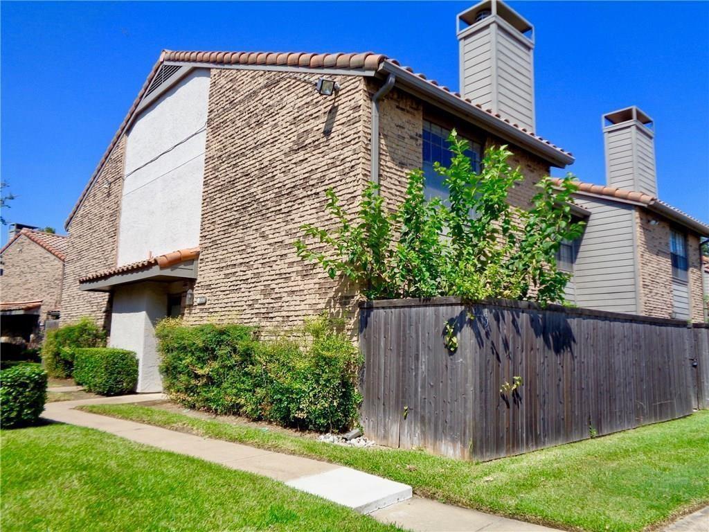 Multi-story exterior featuring textured brick and stucco siding, a tiled roof, dual chimneys, and a private wooden fence