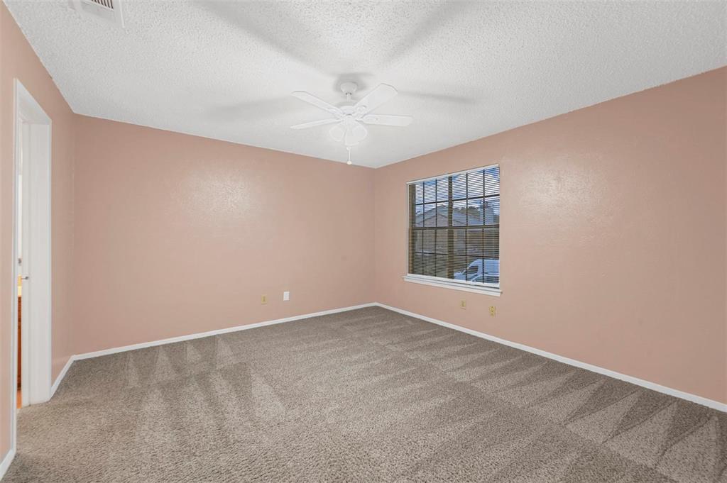 Room featuring neutral wall tones, carpeted flooring, a multi-pane window, and a ceiling fan with integrated light fixture