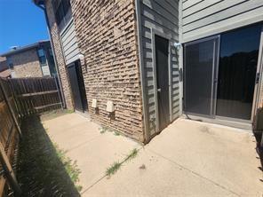 Concrete patio featuring brick exterior siding, horizontal wood-style siding, and sliding glass door entry