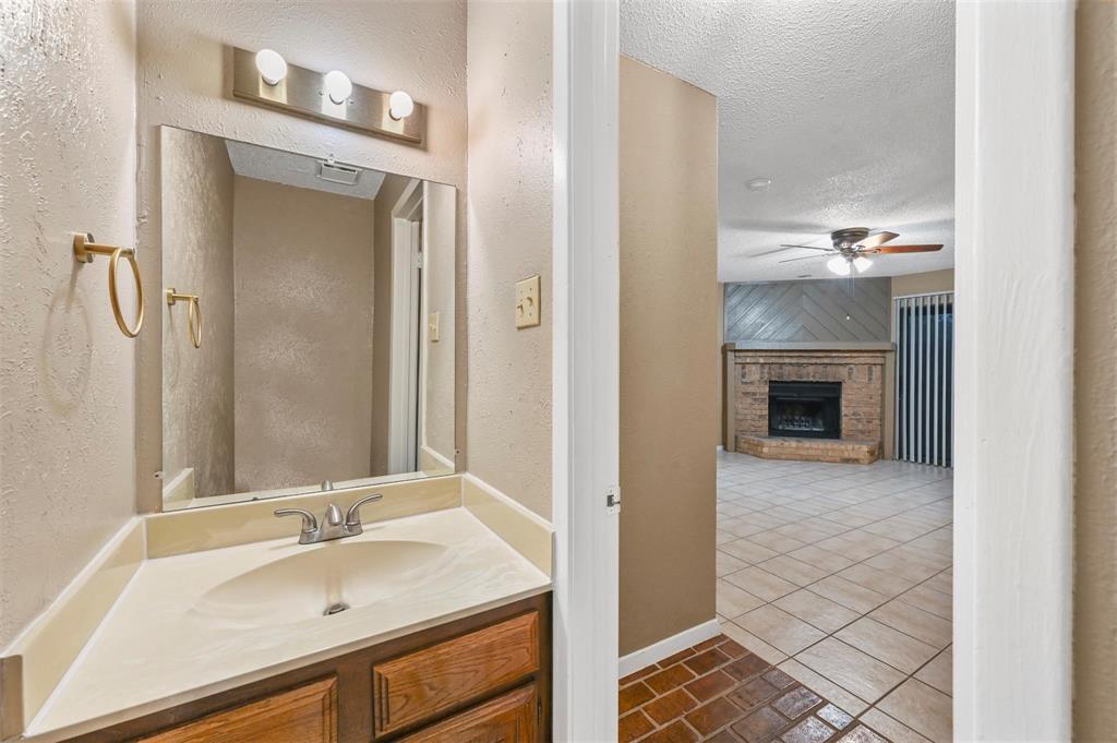 Bathroom featuring a wooden vanity, integrated countertop with sink, and three-light wall fixture