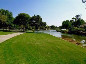 Expansive lawn with mature trees, paved walkway, and direct water frontage