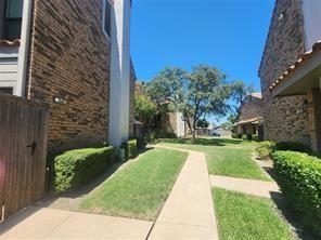 Brick exterior siding, concrete walkways, wood-finish privacy fencing, and manicured landscaping
