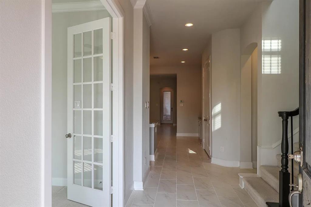 Interior entry featuring large-format tile flooring, recessed lighting, arched doorways, a white French door, and a staircase with a dark wood handrail