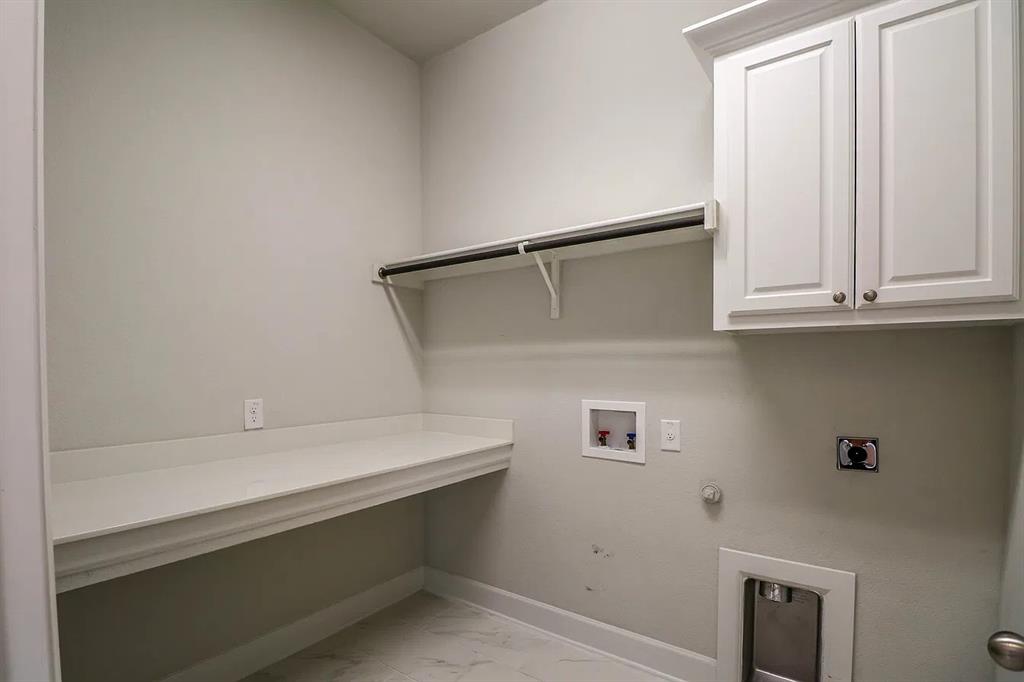 Utility space featuring white shaker-style upper cabinetry, an integrated folding counter, a mounted clothing rod, and tile flooring