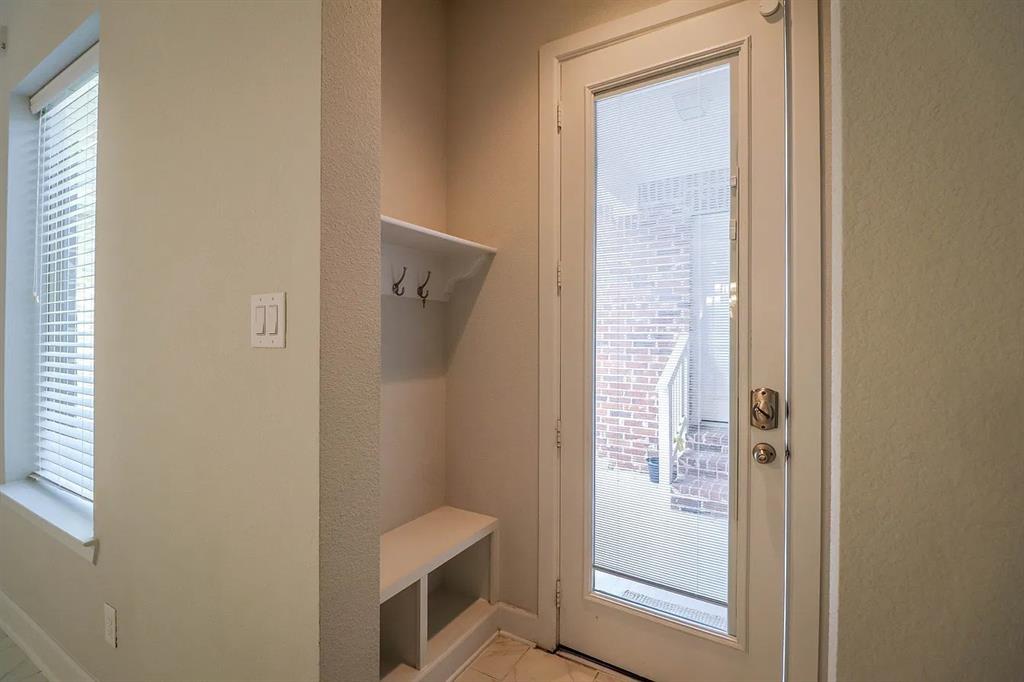Built-in entryway storage featuring a bench seat, shelving, and double hooks, paired with a full-lite glass door