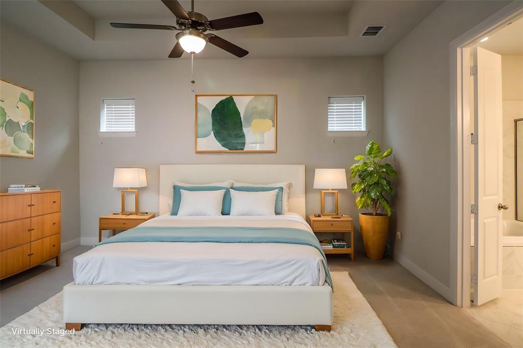 Bedroom featuring tray ceiling, ceiling fan with integrated lighting, dual transom windows, and carpeted flooring