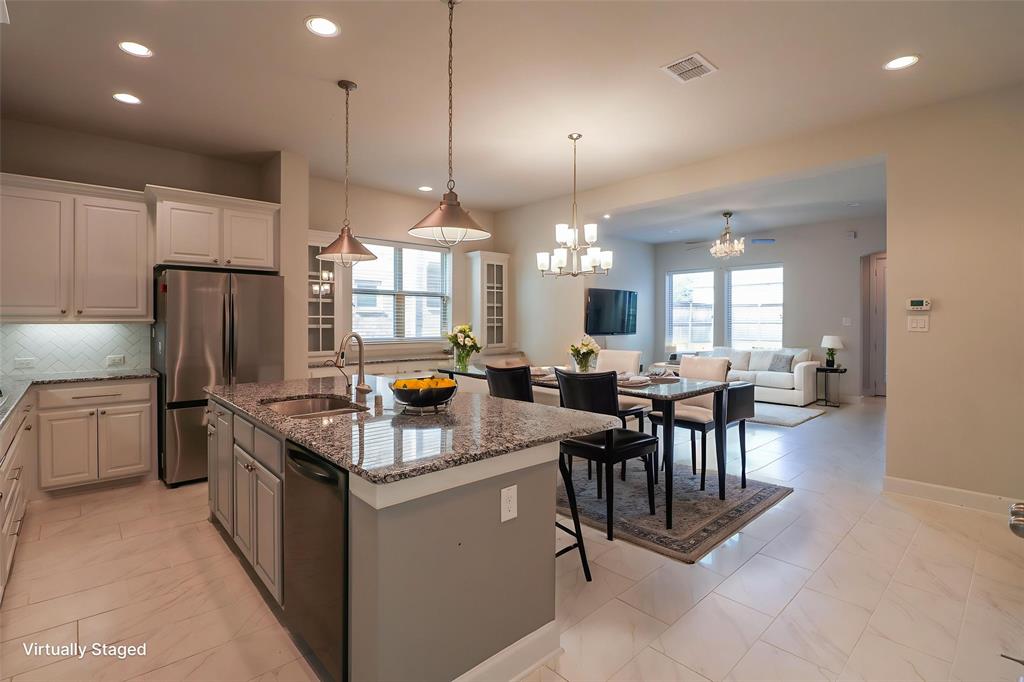 Kitchen featuring a stone-topped island with an under-mount sink, white cabinetry, stainless steel appliances, and tile flooring