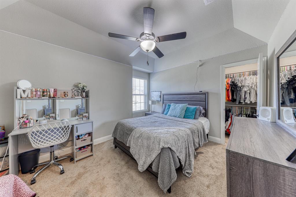 Tray ceiling featuring a central ceiling fan with integrated lighting, neutral wall tones, carpeted flooring, and a walk-in closet