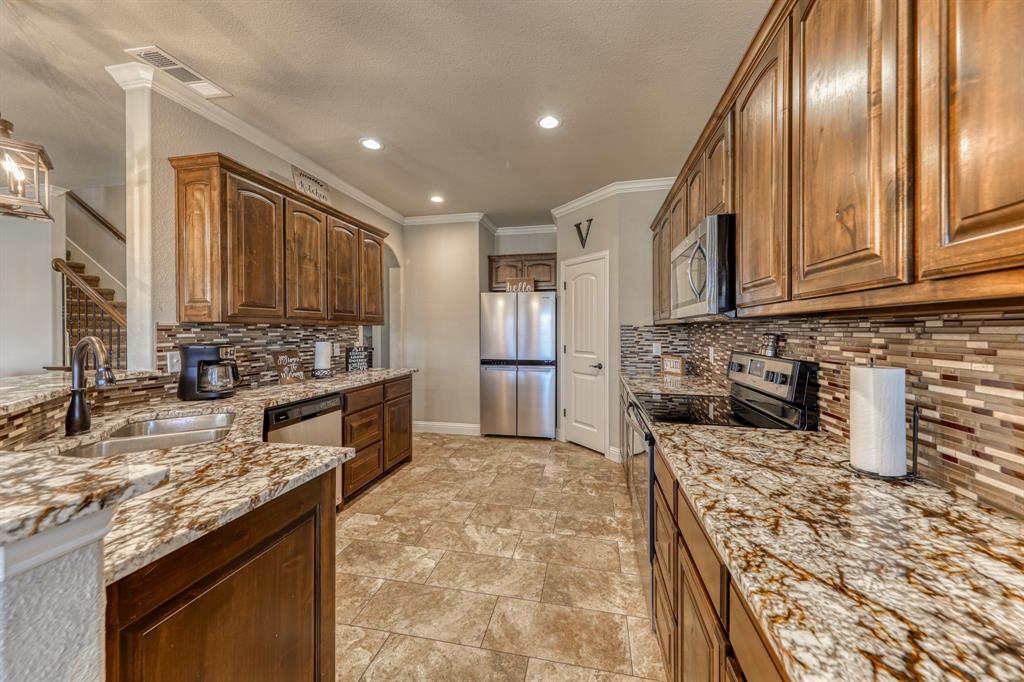 Kitchen featuring wood cabinetry, stone-surface countertops, tile backsplash, stainless steel appliances, and tile flooring