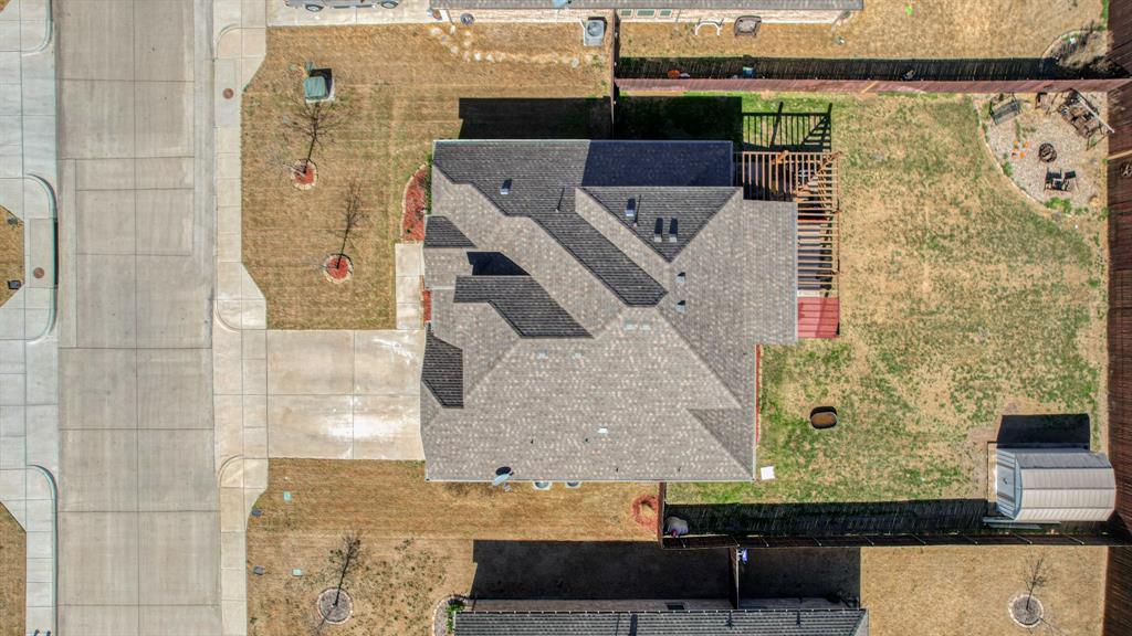 Aerial perspective featuring an asphalt shingle roof, a backyard wood pergola, a perimeter wood fence, and a detached storage structure