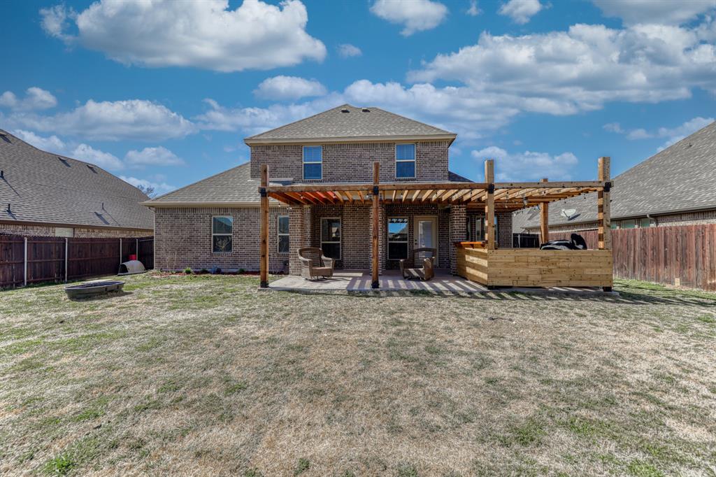 Brick exterior featuring a wooden pergola, concrete patio, and fenced backyard
