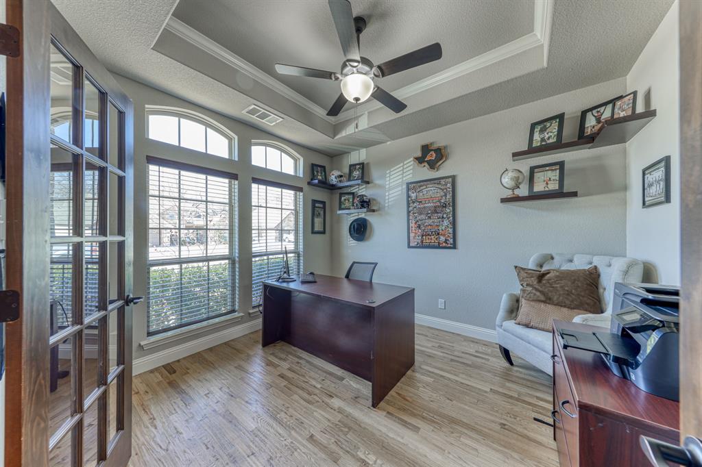 Room featuring a tray ceiling, wood-finish flooring, two large windows with arched transoms, and a French door entry