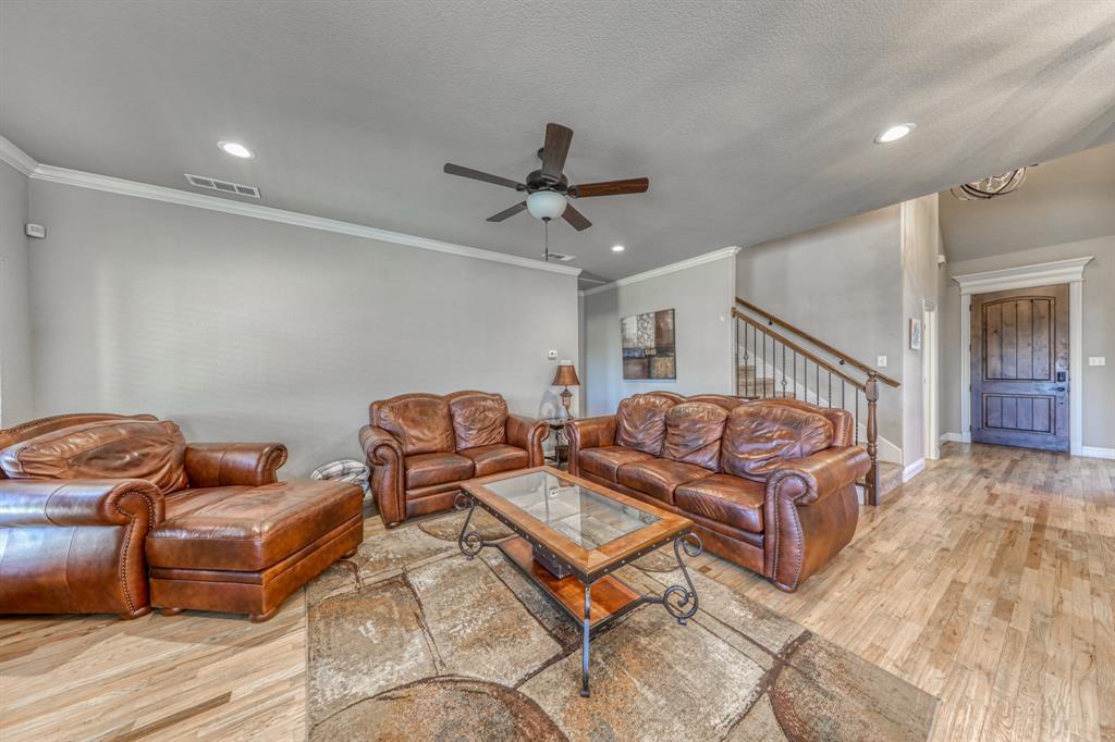 Wood-finish flooring, recessed lighting, ceiling fan with light fixture, staircase with metal balusters, and stained wood entry door