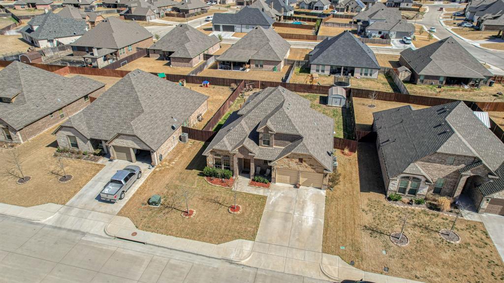 Single-story residence featuring a brick and stone facade, multi-gabled roofline, two-car garage, and a fenced backyard