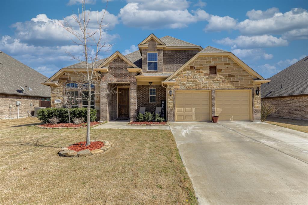 Exterior facade featuring a combination of brick and stone masonry, two-car garage, and arched window detailing