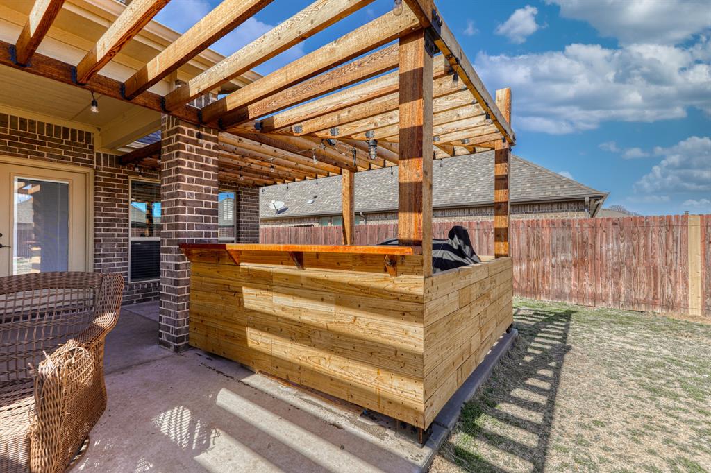 Outdoor space featuring a built-in wooden bar with an overhead pergola, brick exterior siding, concrete patio, and a wood privacy fence