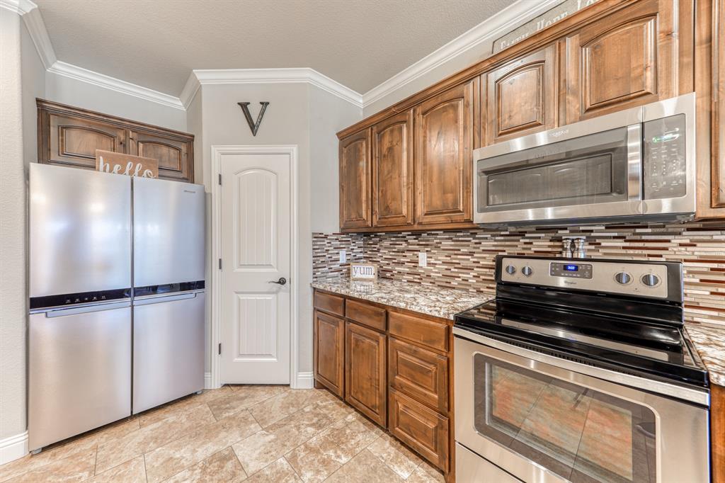 Kitchen featuring stained wood cabinetry, multi-tonal mosaic tile backsplash, stone-surface countertops, and stainless steel appliances