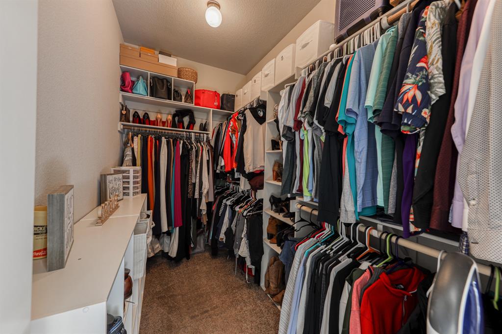 Walk-in closet featuring multi-level hanging rods, floor-to-ceiling built-in shelving, and carpeted flooring