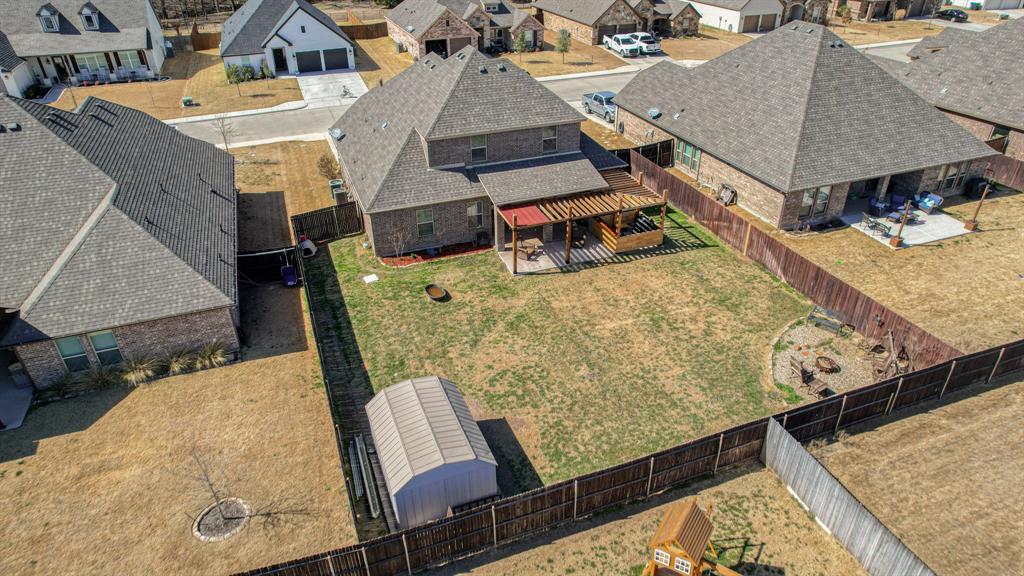 Fenced backyard featuring a wood-frame pergola, a detached metal storage structure, and a perimeter wood fence