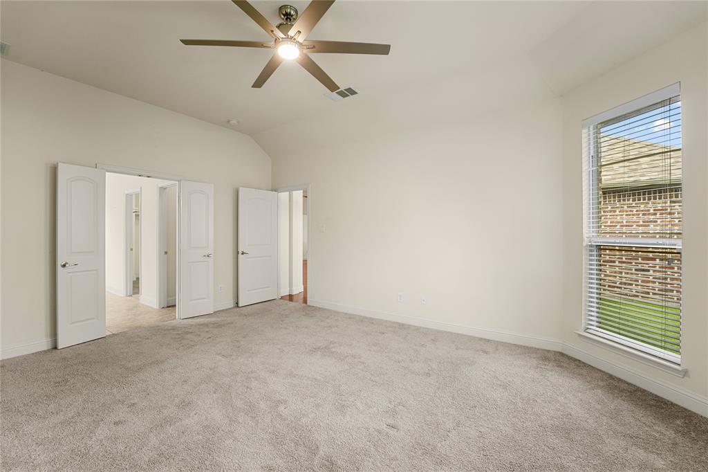 Vaulted ceilings, neutral wall color, wall-to-wall carpeting, ceiling fan with light fixture, and large windows with horizontal blinds