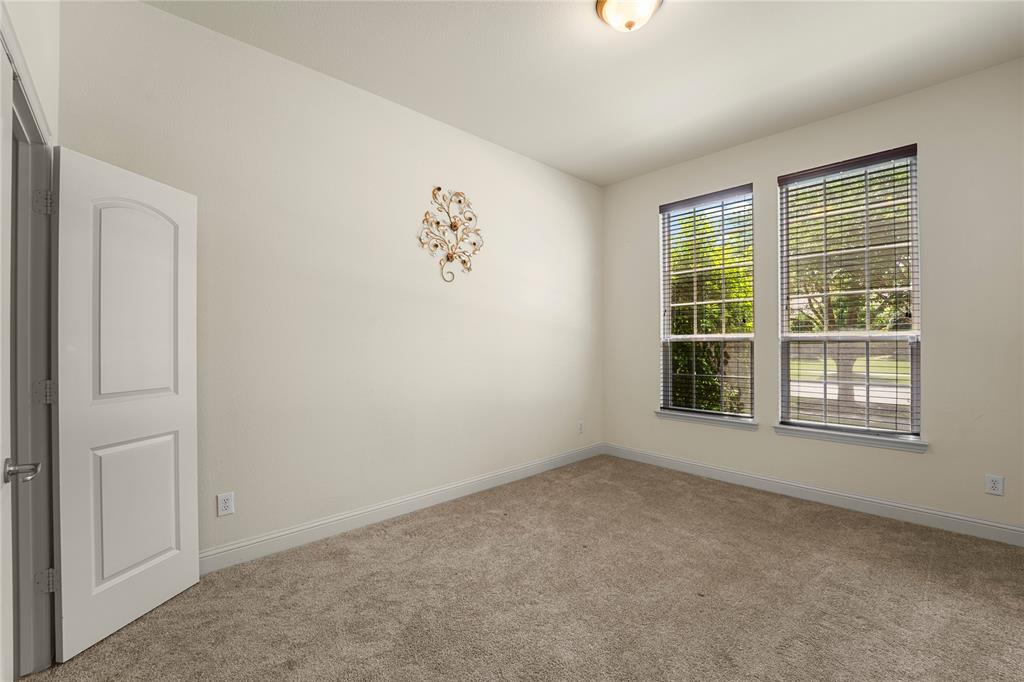 Neutral-toned room featuring plush wall-to-wall carpeting, dual windows with integrated blinds, and a solid-core interior door