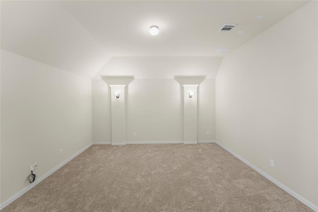 Interior space featuring neutral wall tones, plush wall-to-wall carpeting, two decorative structural columns with built-in wall sconces, and recessed ceiling lighting