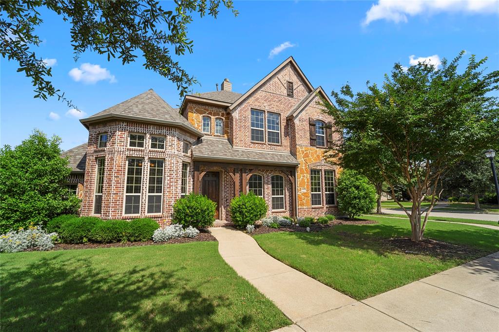 Two-story brick and stone veneer exterior featuring a turret-style roofline, a multi-gabled facade, decorative wood gables, and multi-pane windows
