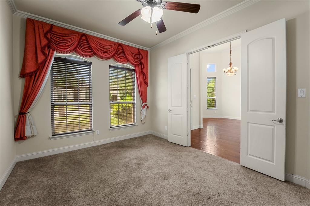 Room featuring carpeting, crown molding, double doors, and a ceiling fan with light fixture