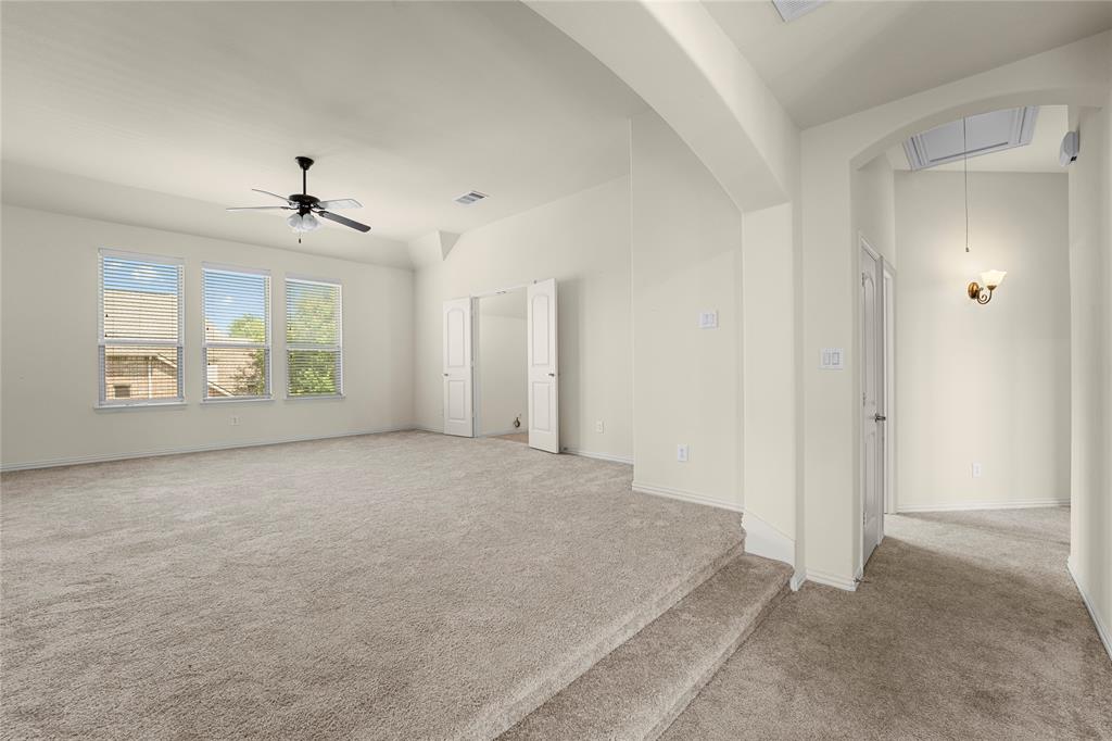 Sunken living area featuring neutral carpeting, high ceilings, multiple double-hung windows, a ceiling fan, and an arched entryway