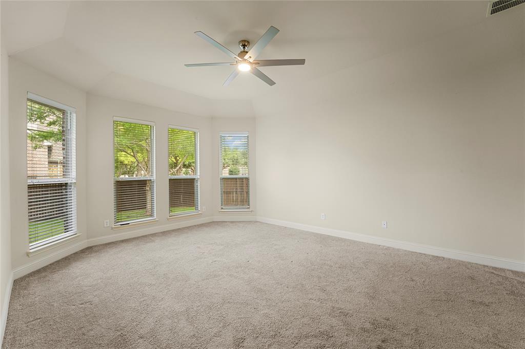 Neutral-toned interior featuring a vaulted ceiling, wall-to-wall carpeting, a multi-pane bay window assembly, and a ceiling-mounted fan with integrated lighting