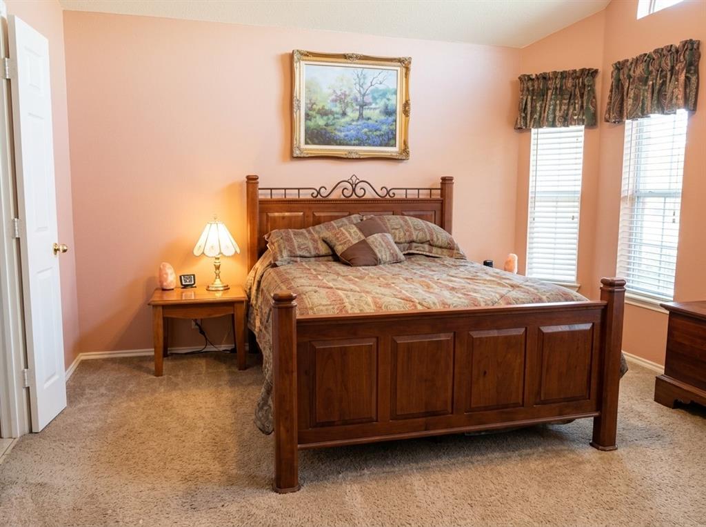 Vaulted ceilings, neutral carpeting, and multiple windows with horizontal blinds