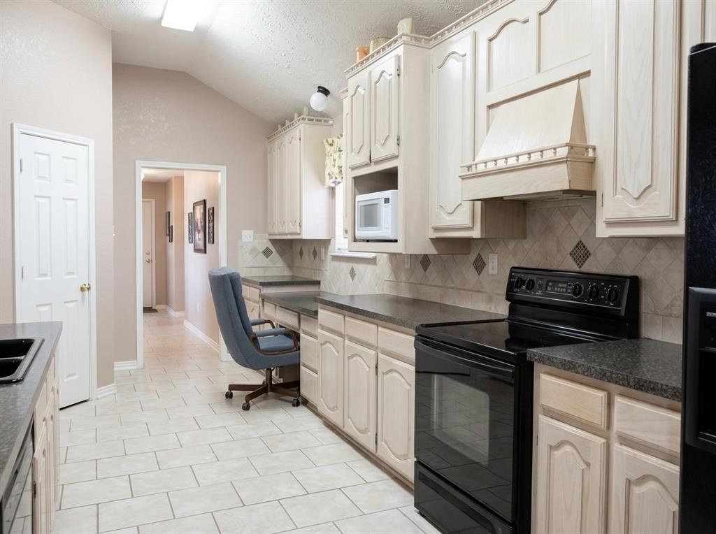 Kitchen featuring arched-panel cabinetry, vaulted ceiling, stone-finish countertops, ceramic tile flooring, and a built-in range hood