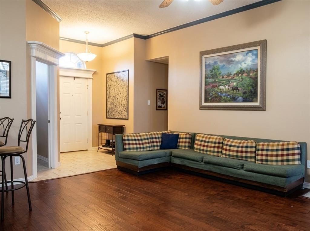 Entryway featuring tiled flooring, crown molding, and a transom window above the front door, finished with wood-finish flooring in the main room