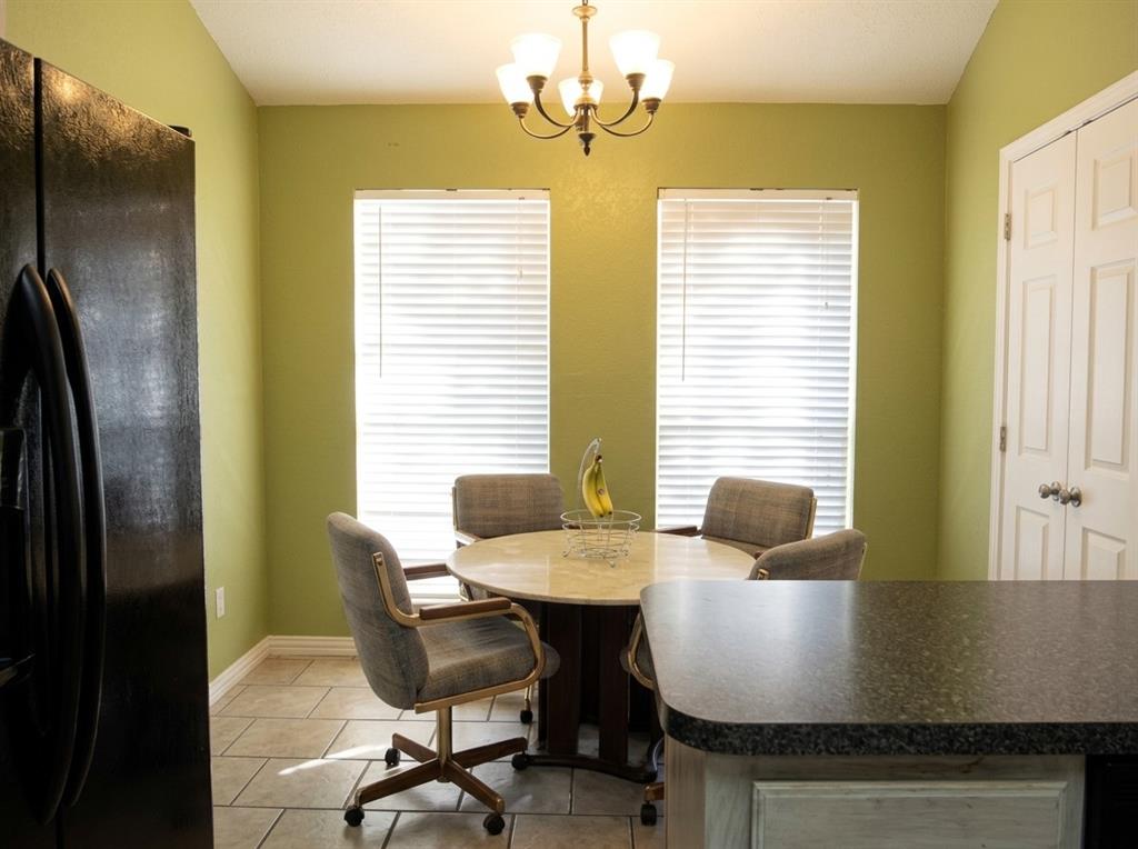Kitchen nook featuring ceramic tile flooring, dual windows with blinds, a multi-arm chandelier, and built-in closet storage