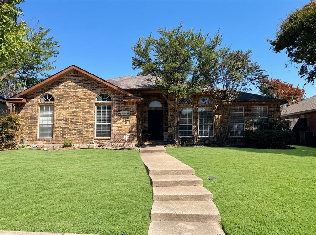 Single-story brick exterior featuring a multi-gabled roofline, arched window detailing, and a concrete walkway