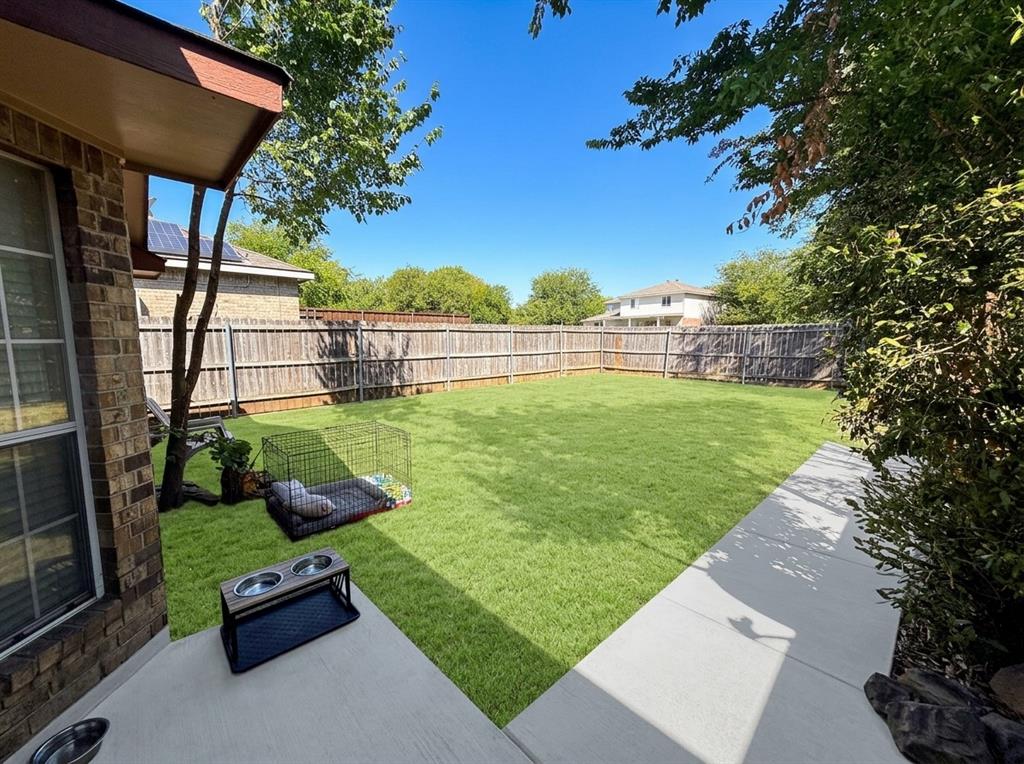Rear exterior featuring a concrete patio, sodded lawn, and perimeter wood privacy fencing