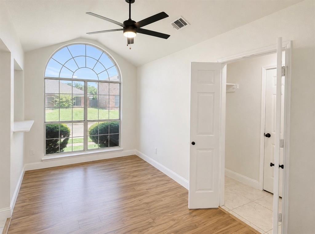 Vaulted ceiling featuring an arched window, wood-finish flooring, and a matte black ceiling fan