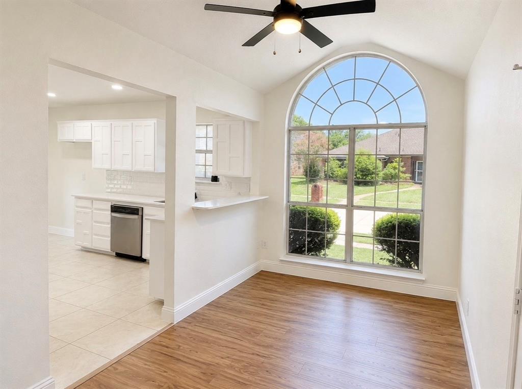 Vaulted ceilings, large arched window, wood-finish flooring, and built-in ceiling fan